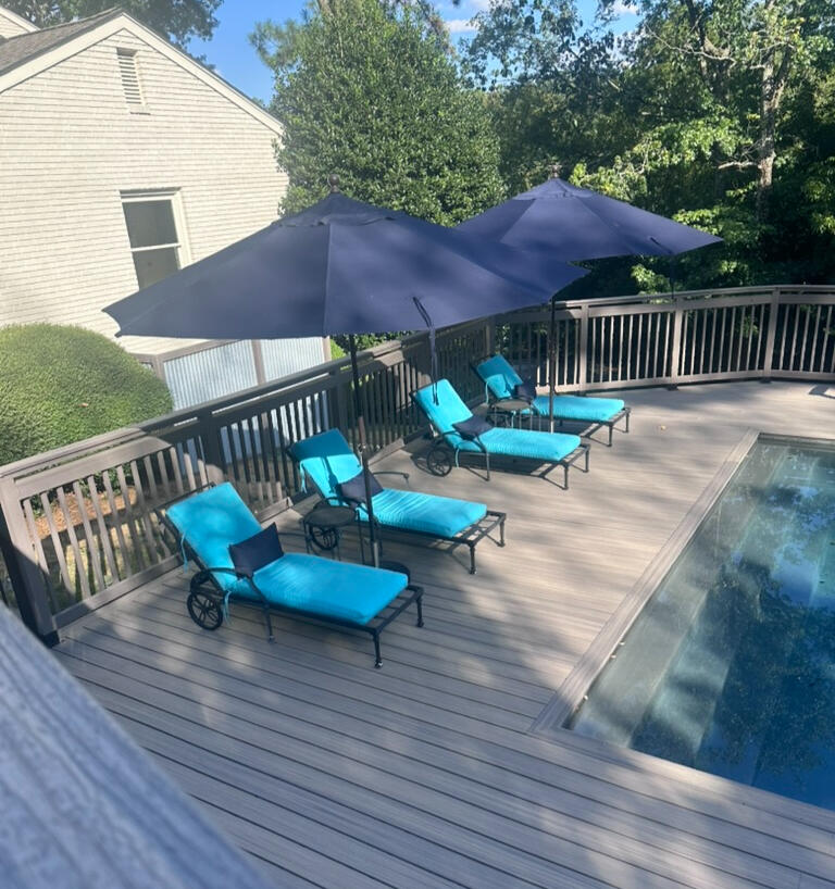 Trex Composite Deck by the pool a photo of a composite pool deck with light blue cushions and black lounge chairs