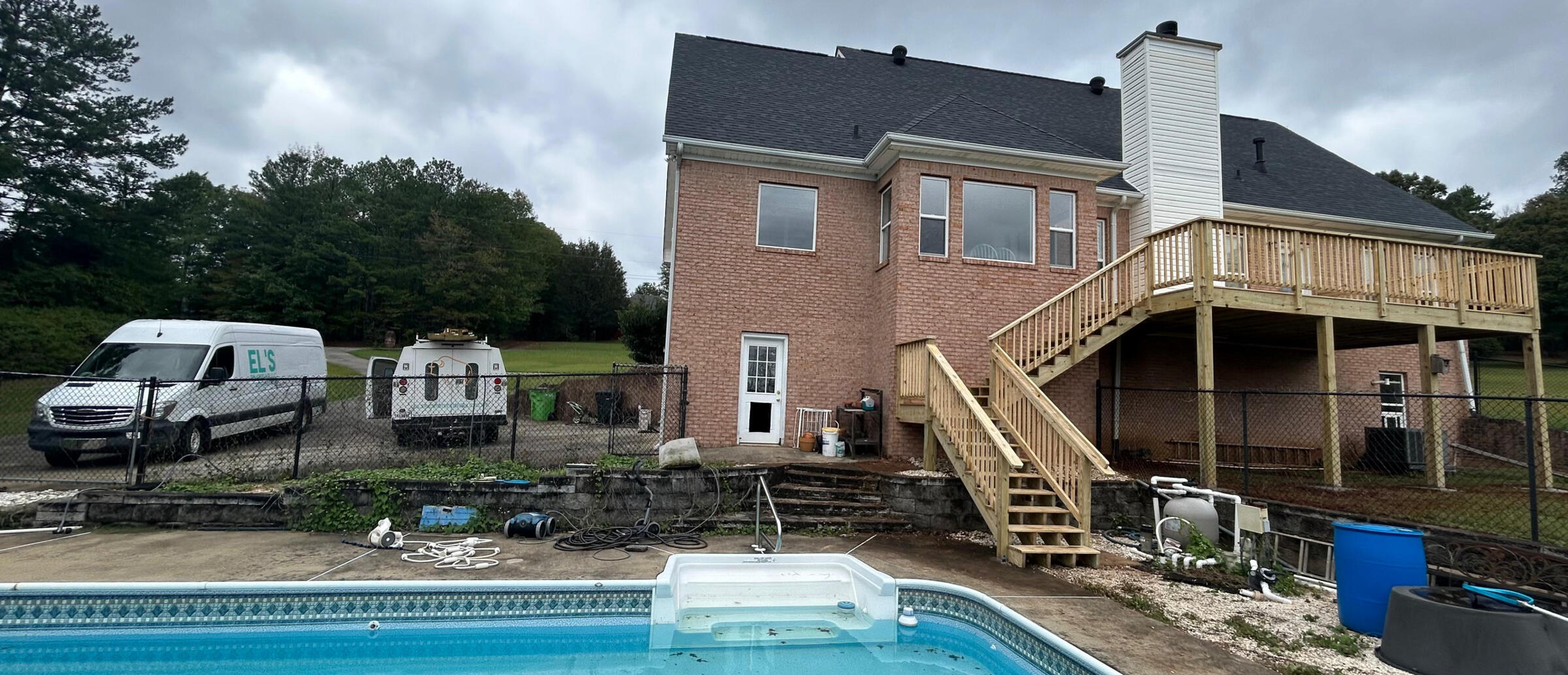 pressure treated deck by the pool with two work vehicles in the background
